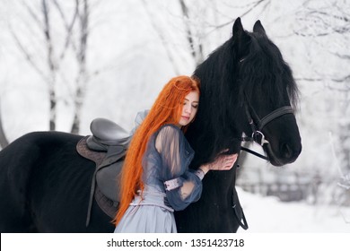 Redhead beautiful girl in a dress 
hug Frisian horse with long mane on winter background