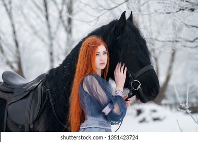 Redhead beautiful girl in a dress 
near Frisian horse with long mane on winter background