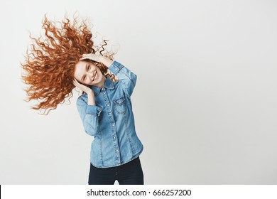 Redhead beautiful girl smiling looking at camera smiling shaking curly hair. White background.