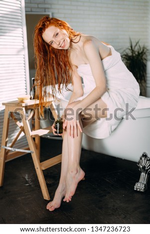 Redhead beautiful young woman applying coffee body scrub on legs, closeup. Feet treatment. Beauty treatment for legs. Hand massaging feet with coffee grounds.