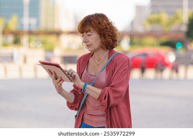 Redhead businesswoman using digital tablet while standing in a city street - Powered by Shutterstock