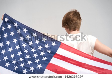 Redhead caucasian girl holds usa flag behind her back