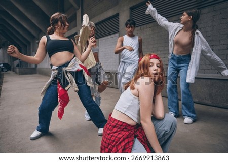 Redhead dancer posing in front with dramatic emotion during group street dance. Concept of youth culture, lifestyle passion, dance schools, fashion branding and creative social media content.