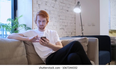 Redhead Designer Using Smartphone in Creative Office
