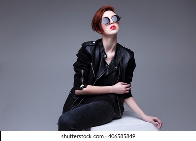 Redhead Fashion Model In Sunglasses And Black Leather Jacket. Pixie Cut Hairstyle. Punk, Rock Style Fashion