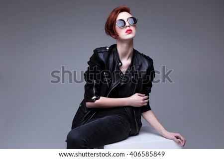 Redhead fashion model in sunglasses and black leather jacket. Pixie cut hairstyle. Punk, rock style fashion