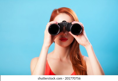 Redhead Girl With Binocular On Blue Background.