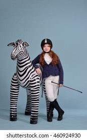 Redhead Girl With Freckles In Riding Clothes And Helmet On A Light Background With A Bouncy Horse, The Jockey Concept, Concept Dream