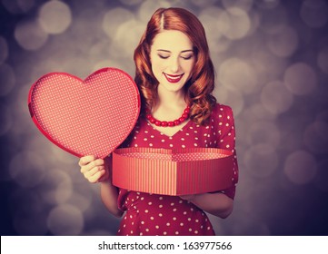 Redhead girl with gift for Valentines Day. Photo with bokeh at background