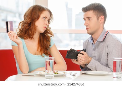 redhead girl paying for lunch instead of man. man showing empty wallet to girl in cafe