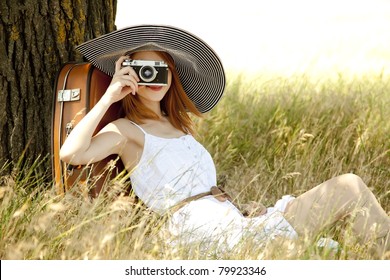 Redhead girl sitting near tree with vintage camera. - Powered by Shutterstock