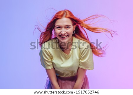 Redhead girl smiling on pink-purple background
