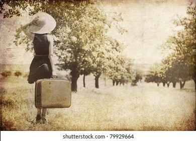 Redhead girl with suitcase at countryside. Photo in old image style.