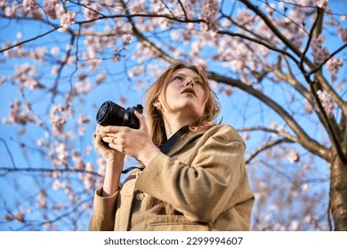 redhead girl taking photos in front of cherry blossom - Powered by Shutterstock