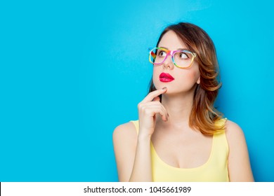 Redhead girl in yellow dress and colored glasses on blue background  - Shutterstock ID 1045661989