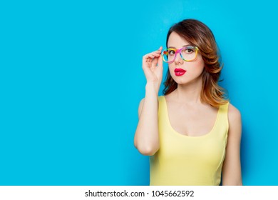 Redhead girl in yellow dress and colored glasses on blue background  - Shutterstock ID 1045662592