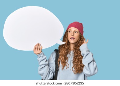 Redhead holding a comic speech bubble trying to listening a gossip.