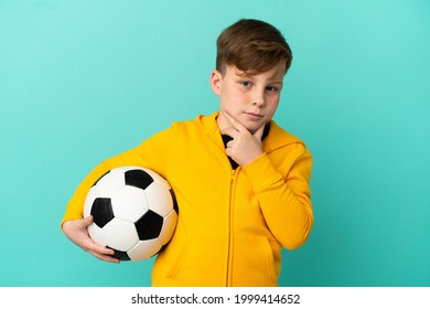 Redhead Kid Playing Football Isolated On Blue Background Thinking