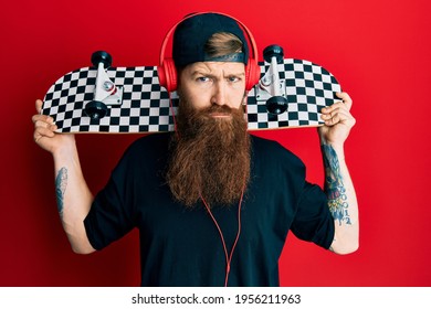 Redhead man with long beard holding skate wearing headphones depressed and worry for distress, crying angry and afraid. sad expression.  - Powered by Shutterstock