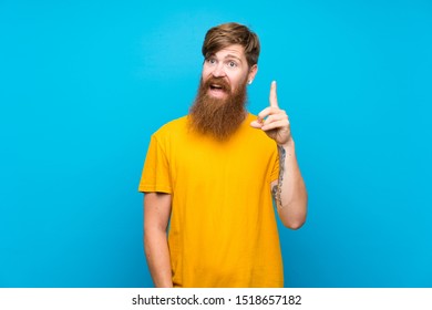 Redhead man with long beard over isolated blue background thinking an idea pointing the finger up - Shutterstock ID 1518657182