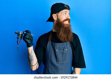 Redhead Man With Long Beard Tattoo Artist Wearing Professional Uniform And Gloves Looking Away To Side With Smile On Face, Natural Expression. Laughing Confident. 