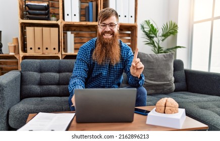 Redhead Man With Long Beard Using Laptop Working At Psychology Clinic Smiling Happy Pointing With Hand And Finger To The Side 