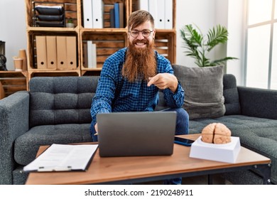 Redhead Man With Long Beard Using Laptop Working At Psychology Clinic Smiling Happy Pointing With Hand And Finger 