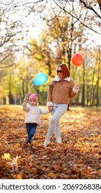 Redhead Mom With White-haired Daughter Are Playing In The Autumn Forest