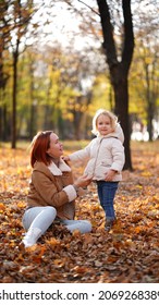 Redhead Mom With White-haired Daughter Are Playing In The Autumn Forest