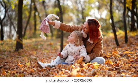 Redhead Mom With White-haired Daughter Are Playing In The Autumn Forest