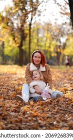 Redhead Mom With White-haired Daughter Are Playing In The Autumn Forest