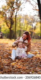 Redhead Mom With White-haired Daughter Are Playing In The Autumn Forest