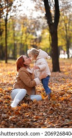 Redhead Mom With White-haired Daughter Are Playing In The Autumn Forest