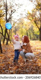 Redhead Mom With White-haired Daughter Are Playing In The Autumn Forest