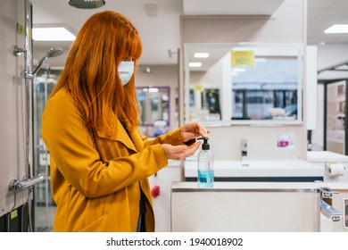 Redhead Spanish Woman Wearing A Face Mask Applying Hand Sanitizer In The Store