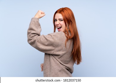 Redhead Teenager Girl With Sweater Over Isolated Blue Background Making Strong Gesture