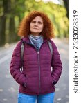 Redhead woman with backpack and purple coat closeup portrait in a park