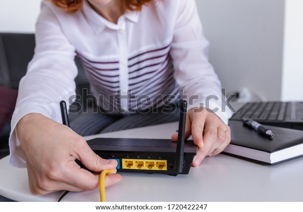 Redhead Woman connects the\
internet cable to the router\'s socket. Fast and wireless internet\
concept