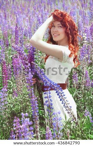 Redhead woman with curly long hair in summer lupine field