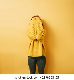 Redhead Woman Hiding Her Face Behind Her Arms, Copyspace Against Yellow Background