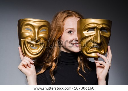 Redhead woman iwith masks in hypocrisy consept against grey background