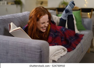 Redhead Woman Laughing While Reading A Funny Book