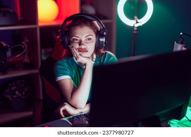 Redhead woman playing video games thinking looking tired and bored with depression problems with crossed arms.  - Powered by Shutterstock