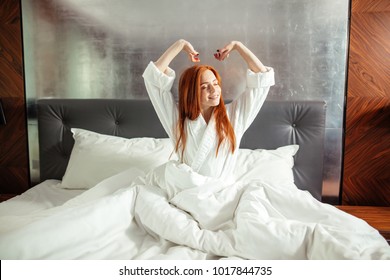 Redhead Woman Stretching In Bed After Waking Up, Entering A Day Happy And Relaxed After Good Night Sleep