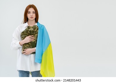 Redhead Woman With Ukrainian Flag Holding Military Uniform Isolated On White