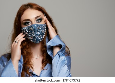 Redhead woman wearing stylish blue protective face mask with pearls, rhinestones, beads. Fashion accessory during quarantine of coronavirus. Close up studio portrait. Copy, empty space for text