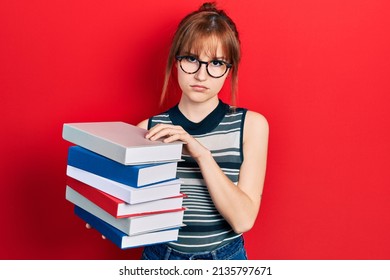 Redhead young woman holding a pile of books depressed and worry for distress, crying angry and afraid. sad expression. 
