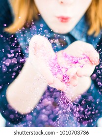 Redheaded Child Blowing Hot Pink Glitter From Hands