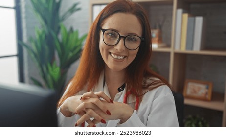 Redheaded woman in glasses and lab coat smiling in a clinic office setting - Powered by Shutterstock