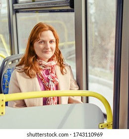 A Redheaded Woman Smiles As She Sits In A Bus Seat